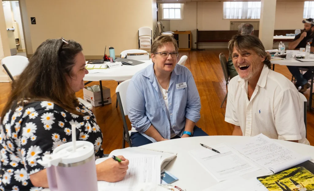 Director of Training & Education Rhonda Andersen laughs with two community members as they collaborate in a group discussion on Wednesday, July 17, 2024.