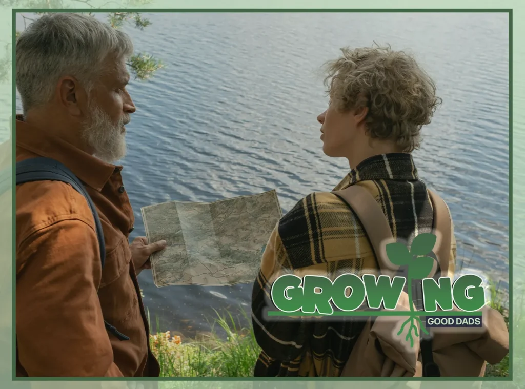 An older father with a white beard stands at a lakeside with his son wearing a backpack. Both look at a map together.