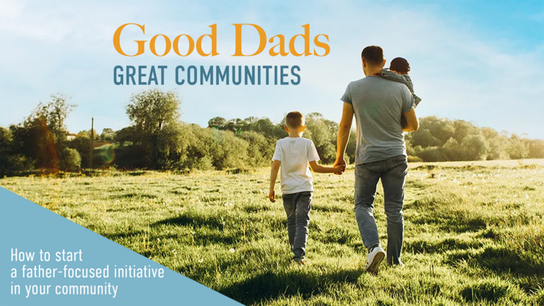 A dad and his two children walk through a green field facing away from the camera