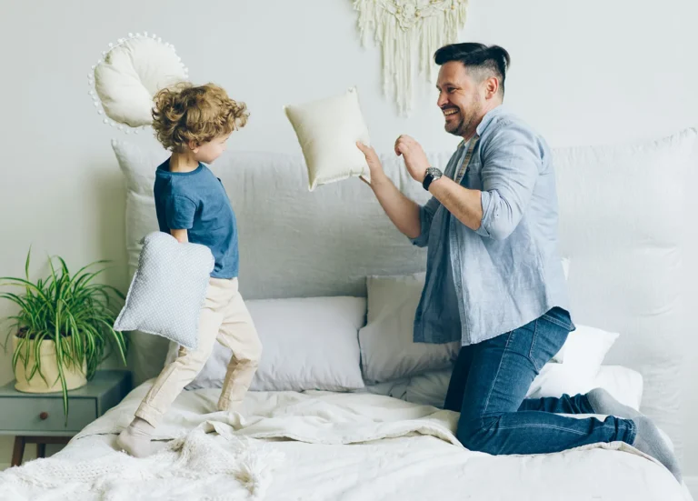 A happy dad and his son have a pillow fight