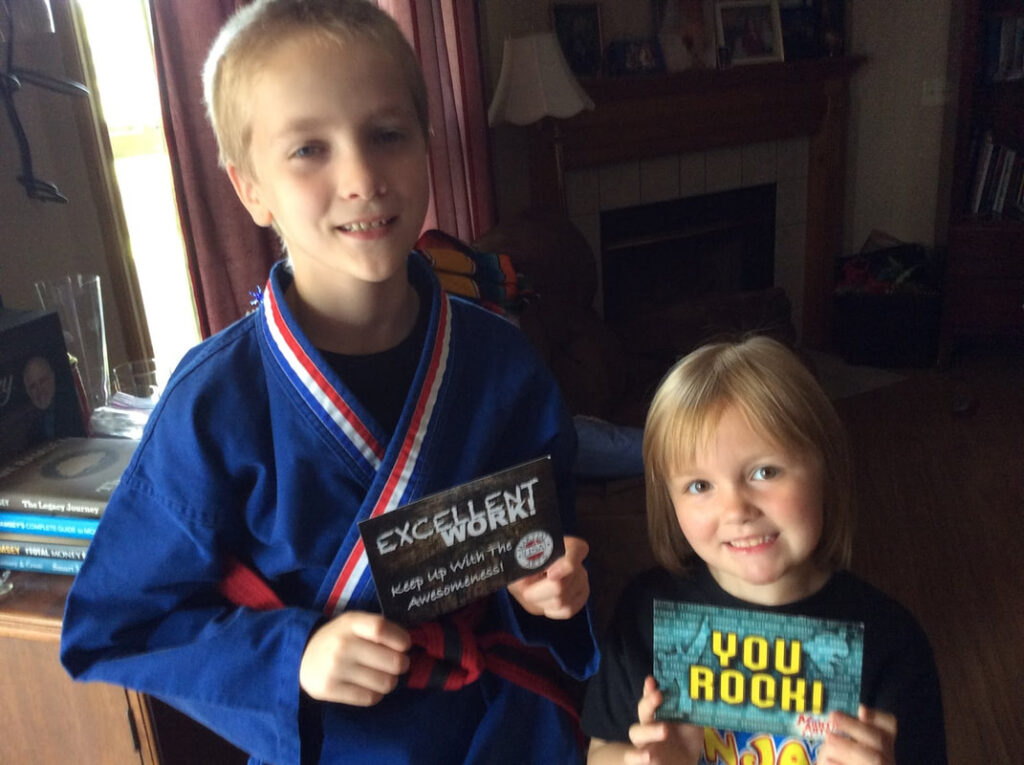 Two happy children hold postcards that say "Excellent Work" and "You Rock!"