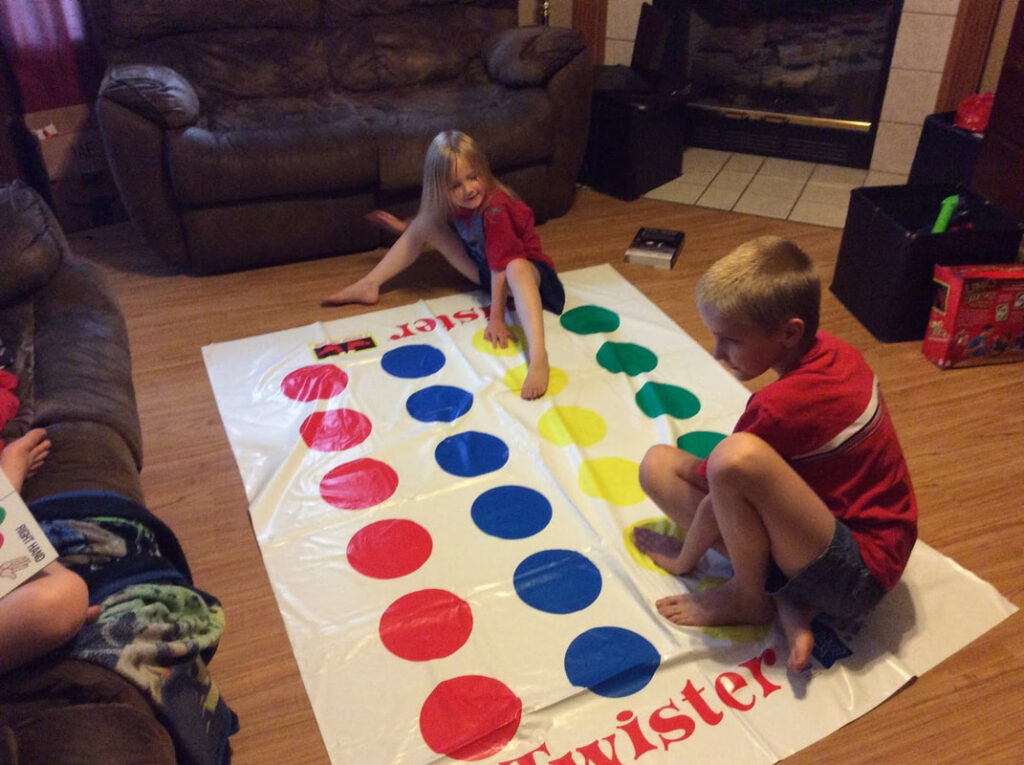 Two children play Twister on the living room floor.