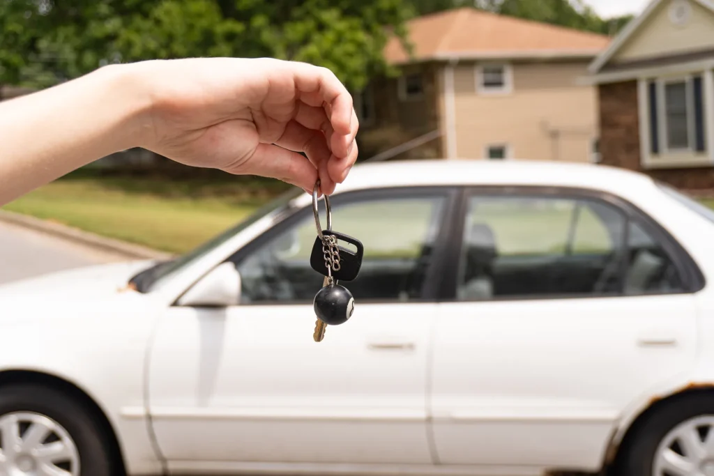 A shallow-focus image of a set of keys dangling in front of a car