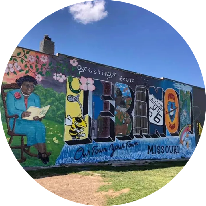 A large mural on the side of a brick building with illustrations of the town of Lebanon