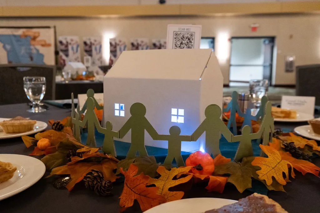 A table centerpiece with fall decor and a cardboard house.