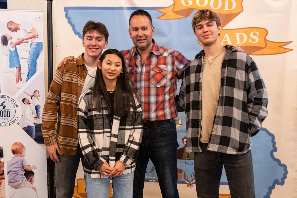 A dad and his three children smile for a group photo.