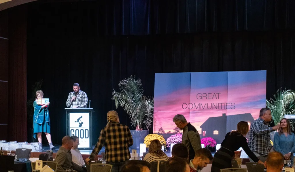 Two people standing on a stage near a podium that says Good Dads.