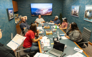 A group of employees sit at a conference room table to discuss fatherhood topics.