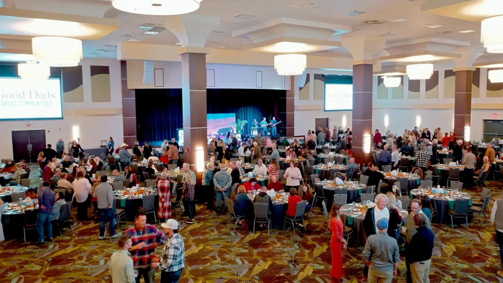 A high-angle shot of a ballroom with guests mingling near a stage.