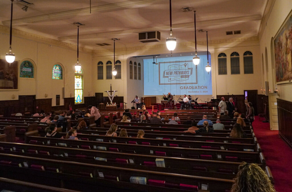 Guests sit in pews and listen to music at the front of the church sanctuary