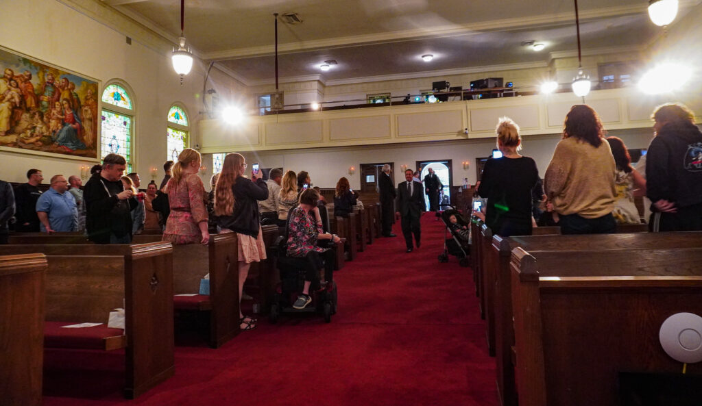 Dads in suits walk down a red carpeted aisle between pews at the Downtown Church in Springfield.