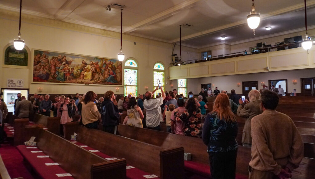 Guests at the Downtown Church stand as program participants walk down the center aisle.