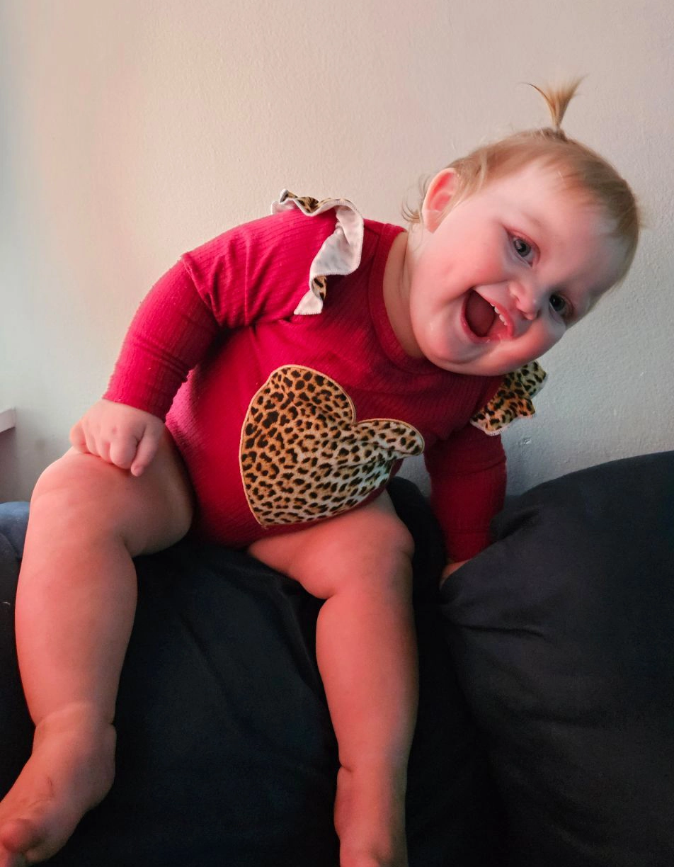 Michael's youngest sits, smiling, on a couch.