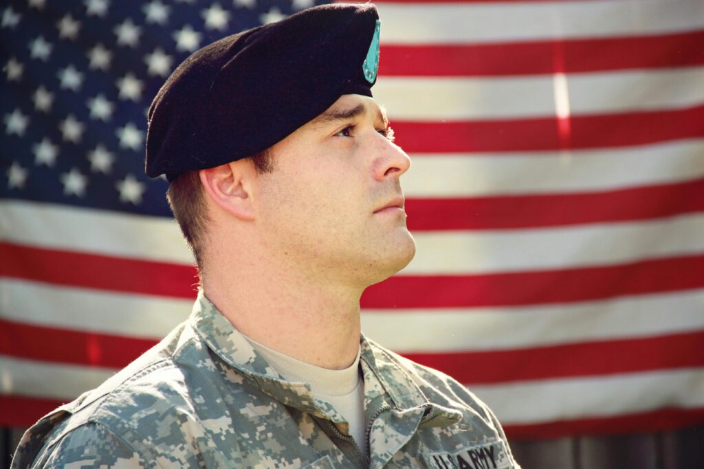 A man with a U. S. Army uniform with an American flag in the background