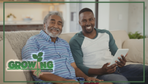 An older dad sits on a couch next to his adult son