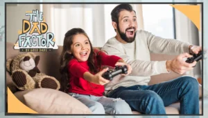 A father and daughter sit side by side on the couch playing video games