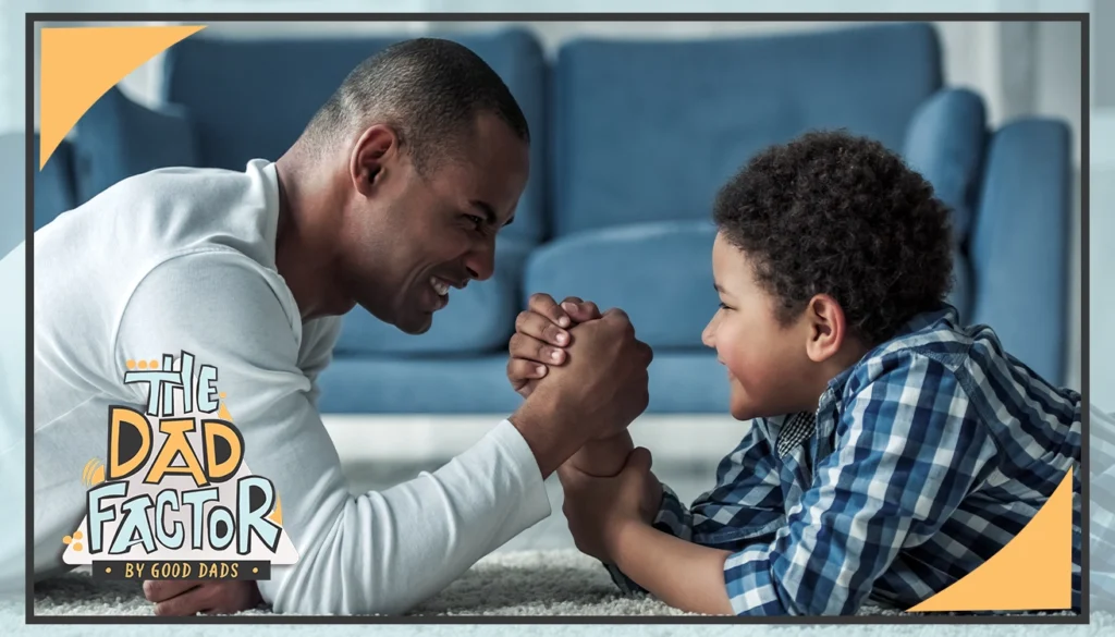 The Dad Factor: A father and son engage in a friendly arm wrestling match on a coffee table in front of a couch