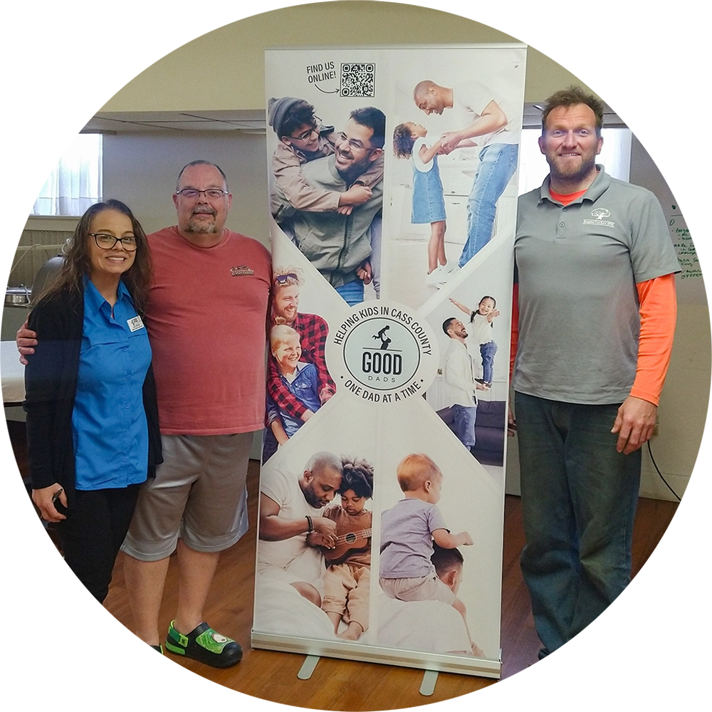 Good Dads Kansas City Admin Assistant Ana Reyes (left) stands with Good Dads Cass County Chapter Leader Bing Schimmelpgenning and Matt Hillbert in front of a Good Dads banner.