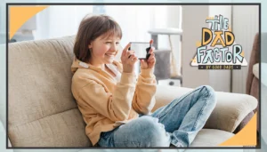 The Dad Factor: A smiling girl sits on a couch, looking at her phone