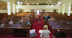 Looking out at the pews, Good Dads founder and director Dr. Jennifer L. Baker stands at a podium at the Downtown Church's Sanctuary to speak to event guests.