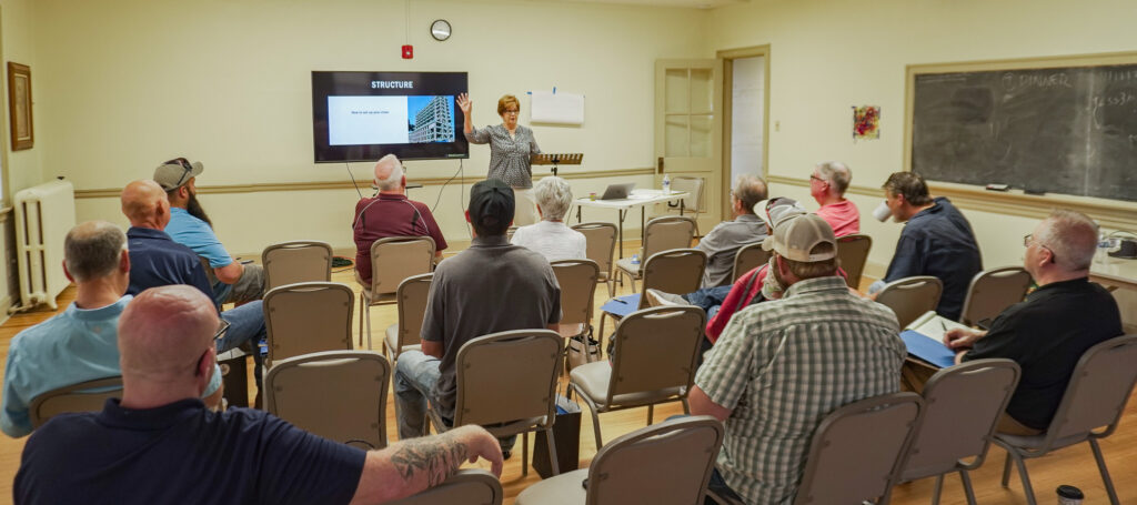 Good Dads board member and master facilitator Sally Herman addresses her group of session attendees in a classroom at the Good Dads Family Reunion