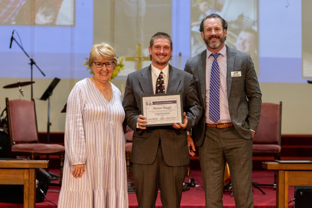 Mason Biaggi holding his graduation certificate next to Dr. Jennifer Baker and Joshua Wemple.