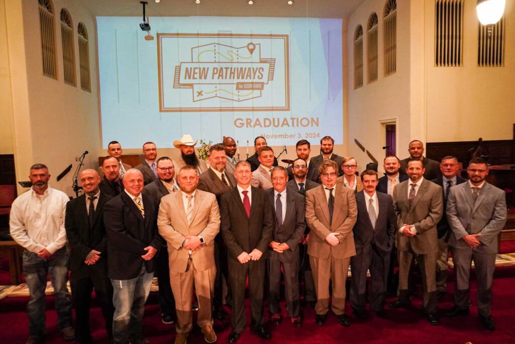 A group of men in suits pose for a group photo during the Good Dads Graduation ceremony