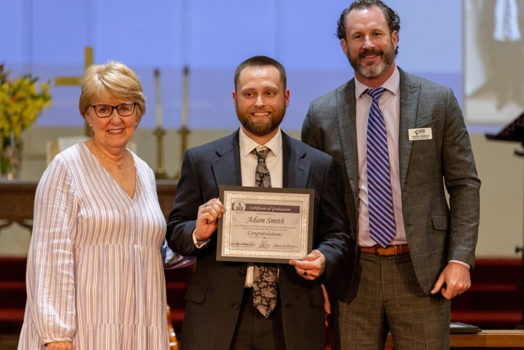 Adam Smith receives graduation certificate from Dr. Jennifer Baker and Joshua Wemple