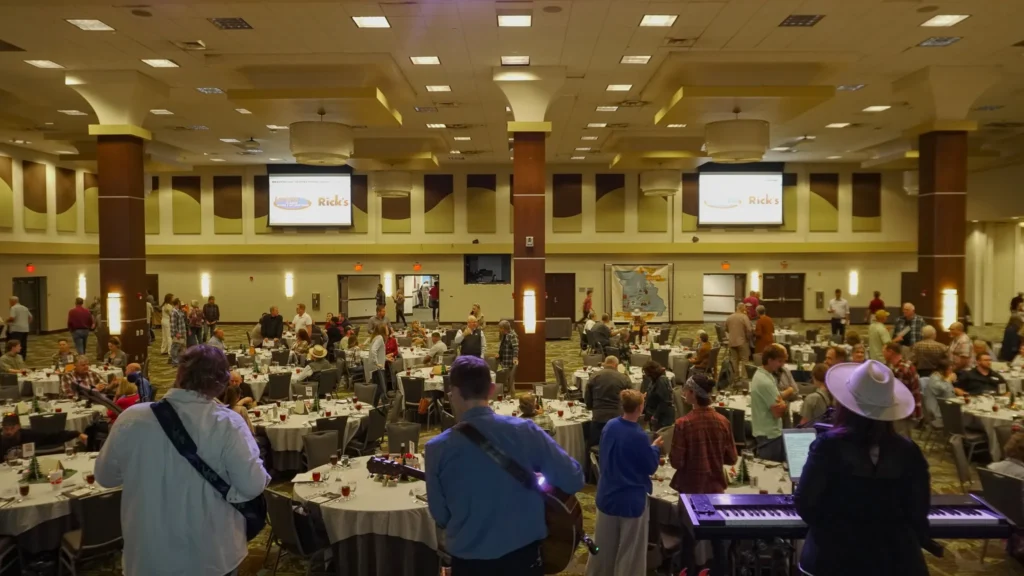 A large group of people scattered around tables in an open ballroom