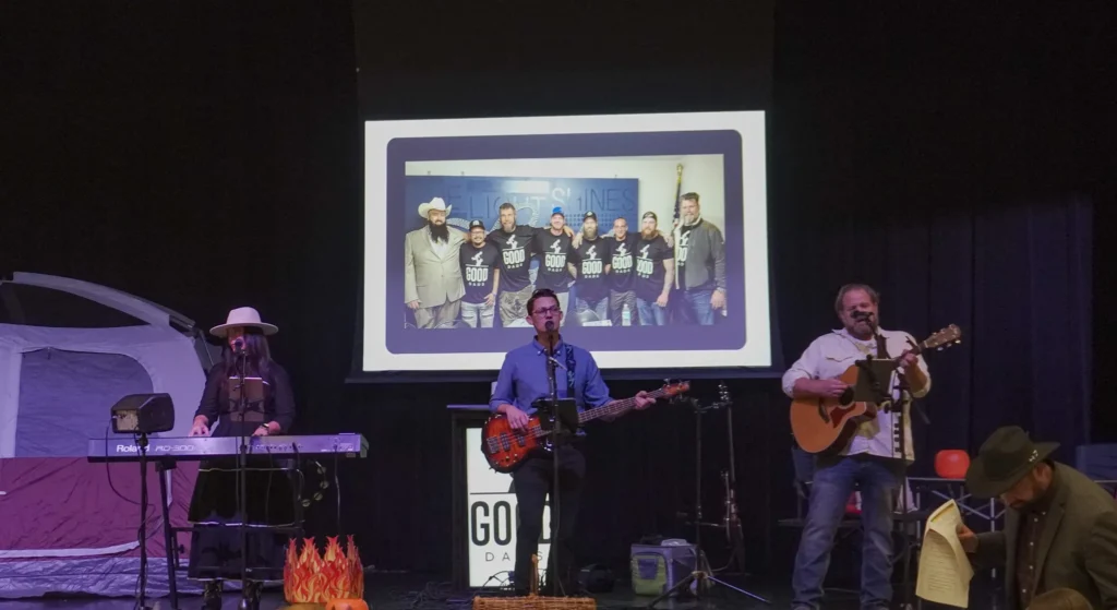 Members of the cover band Deja Crew play on keyboard, bass and acoustic guitar while standing on a stage.