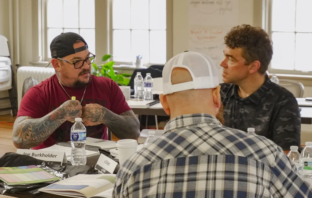 A group of male attendees at Good Dads Training Camp in November 2025 participate in a group discussion in a classroom space at the Downtown Church in Springfield, MO.