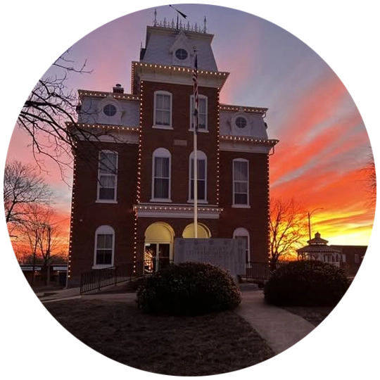 Exterior photo of the Dent County Court House, with a bright red, orange and purple sunset behind the building.