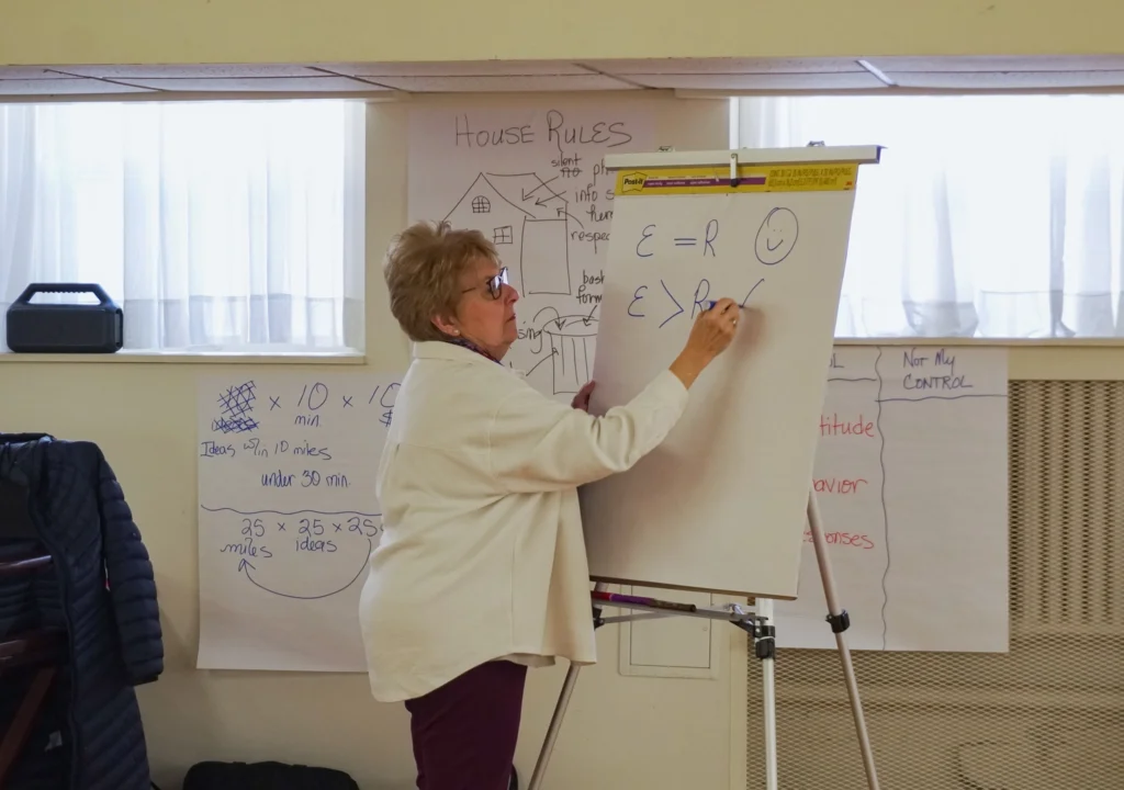 Good Dads Founder and Director Dr. Jennifer L. Baker uses chart paper at the front of the room to take notes during her lecture—making the point that people tend to be happy when their expectations are in line with reality.