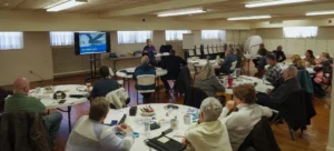 Good Dads founder and director Dr. Jennifer L. Baker stands at the front of the classroom to introduce the "three keys" of healthy communication concept in the Prep 8.0 curriculum at the January 2026 Good Dads Plus Us Training Camp in Springfield MO.