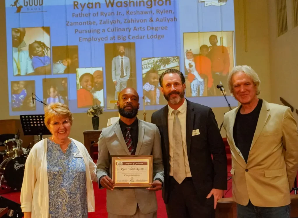 Good Dads graduate Ryan Washington receives his diploma alongside Good Dads founder Dr. Jennifer L. Baker, board chair Joshua Wemple and board member Robert Hawkins at the June 2026 graduation ceremony.
