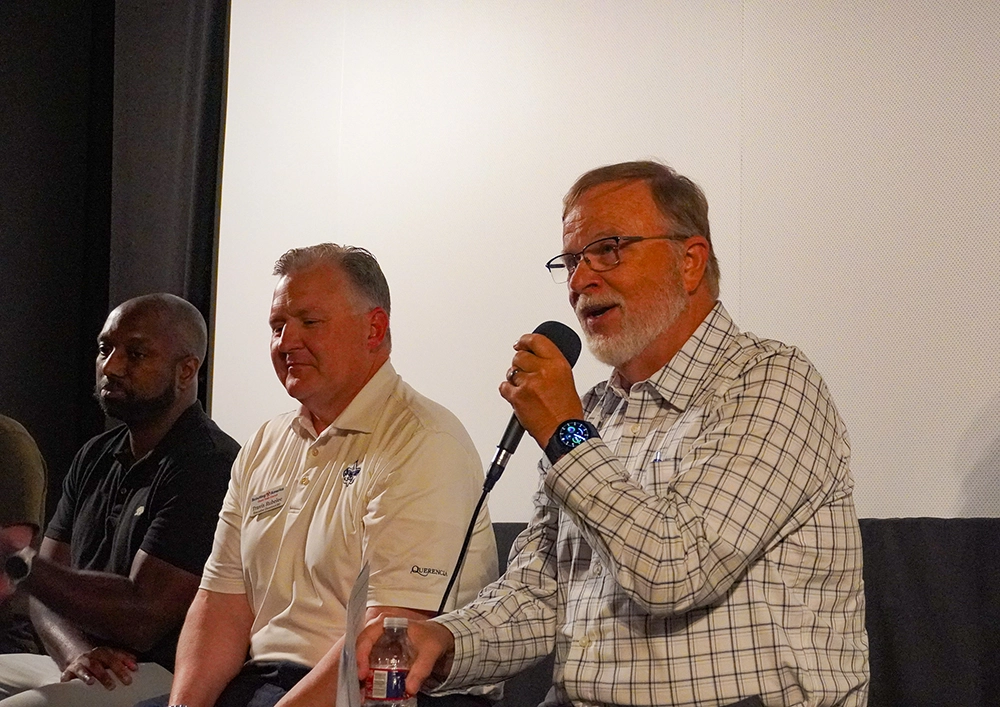 Jim Millsap, a retired educator, holds a microphone as he speaks to the theater following Good Dads' screening of the "Gone Guys" documentary on June 8, 2026, in Springfield, MO.