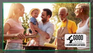 Good Dads Communicators: a group of adults, including a father holding a young child, stand outside on a sunny day