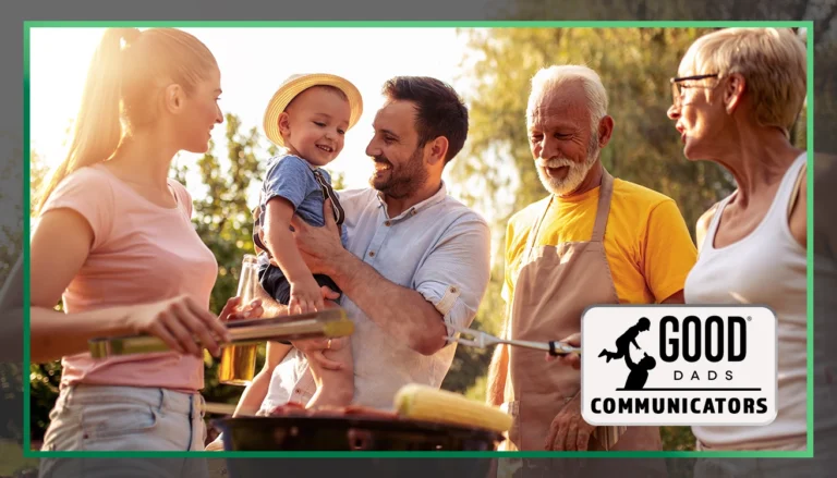 Good Dads Communicators: a group of adults, including a father holding a young child, stand outside on a sunny day