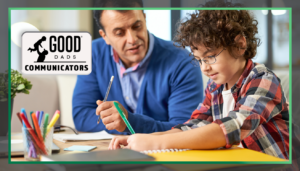Good Dads Communicators: A father sits next to his school-aged son at a desk