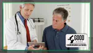 Good Dads Communicators Blog - a middle-aged man wearing a dark blue polo sits in a clinic exam room while a doctor in a white lab coat reads from a touch-screen tablet.