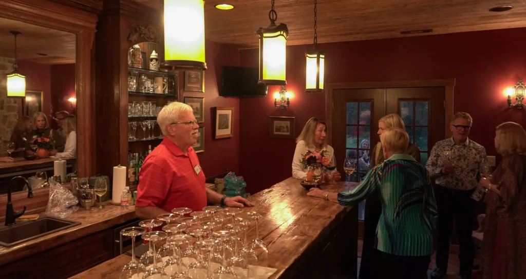 Good Dads supporters mingle at the bar during a reception to celebrate the nonprofit's outcomes, at the home of a Good Dads board member, in October 2026.